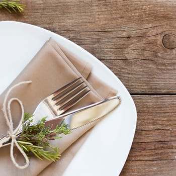 Rustic Table setting with juniper and rosemary decor on old wooden table