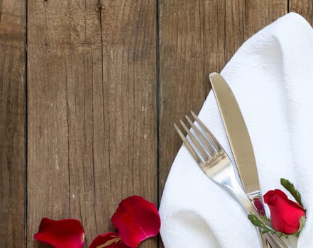 Table setting with rose petals on old wooden table