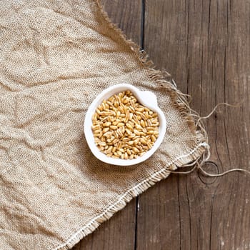 Raw Organic wheat grain in a bowl on wooden table