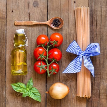 Ingridients for pasta with tomato sauce - tomatoes, onion, basil, extra vergin olive oil, pepper and whole durum spaghetti