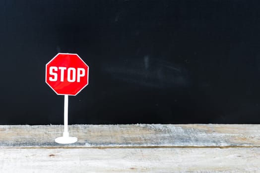 Mini STOP sign over chalkboard background and table, copy space available, concept image
