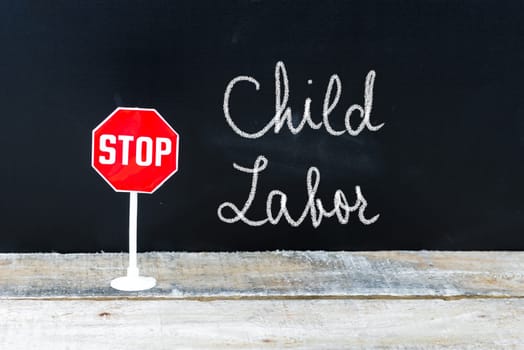 Mini STOP sign over chalkboard background and table, STOP CHILD LABOR concept