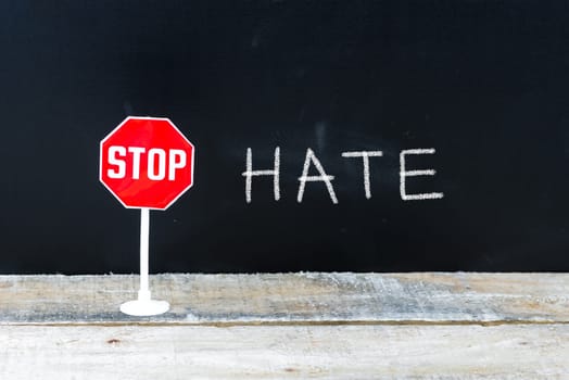 Mini STOP sign over chalkboard background and table, STOP HATE concept