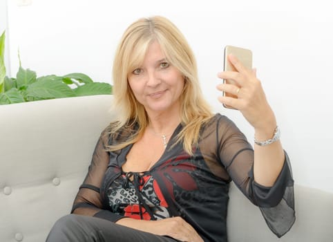 Smiling mature woman using smartphone at home