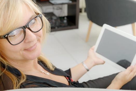 a beautiful mature woman using electronic tablet at home