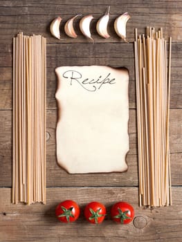 Pasta, tomatoes and garlic on wooden background
