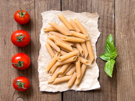 Pasta, tomatoes and basil on wooden background