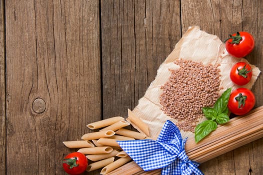 Pasta, tomatoes and basil on wooden background
