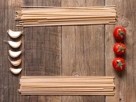 Pasta, tomatoes and garlic on wooden background