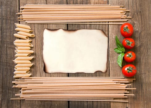 Pasta, tomatoes and basil on wooden background