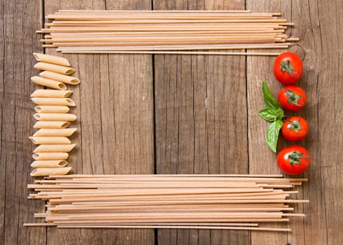 Pasta, tomatoes and basil on wooden background