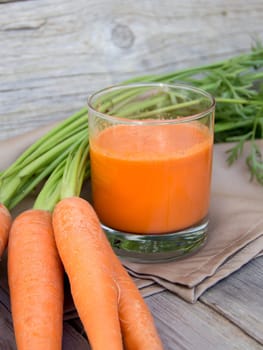 Fresh carrot juice on a wooden background
