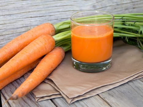 Fresh carrot juice on a wooden background