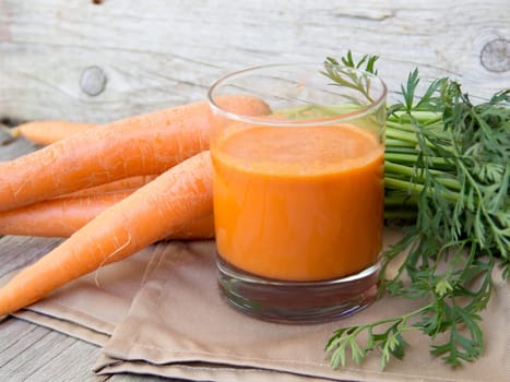 Fresh carrot juice on a wooden background