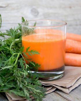 Fresh carrot juice on a wooden background