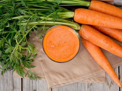 Fresh carrot juice on a wooden background