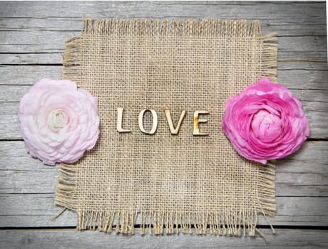 Ranunculus flowers and letters LOVE on wood
