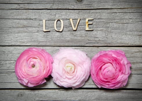Ranunculus flowers and letters LOVE on wood