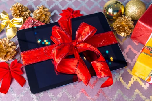 Tablet pc for Christmas with gifts, decorations on table.