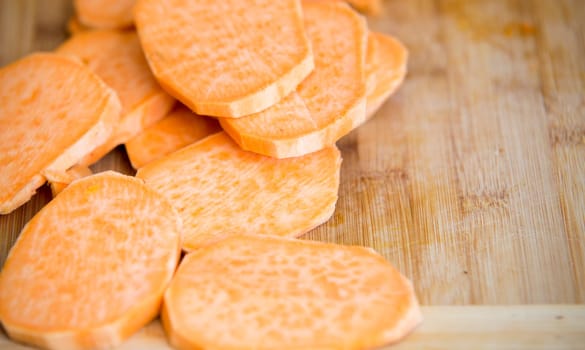 raw pieces of sweet potatoes on wooden background