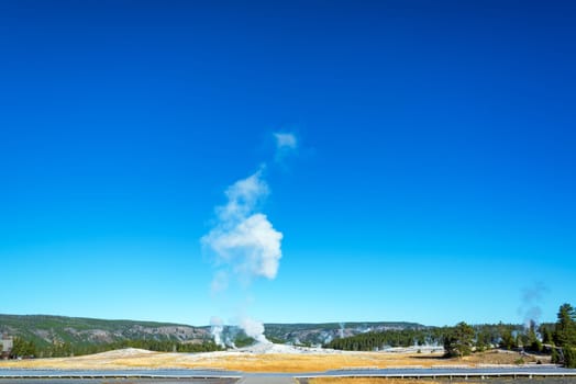 Wide angle view of Old Faithful geyser and viewing platform in Yellowstone National Park