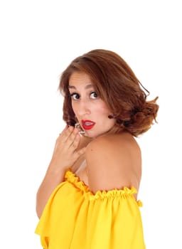 A beautiful woman in a yellow blouse looking surprised into the camera,.with hand over mouth, isolated for white background..
