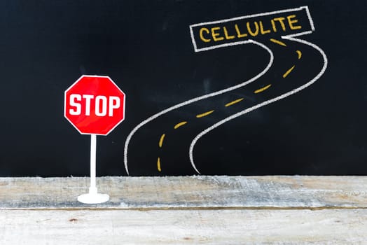 Mini STOP sign on the road to CELLULITE, hand drawing over chalkboard