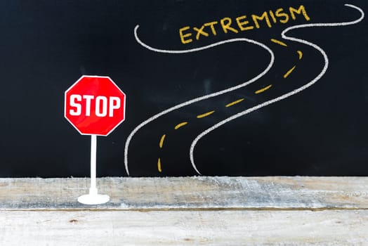 Mini STOP sign on the road to EXTREMISM, hand drawing over chalkboard