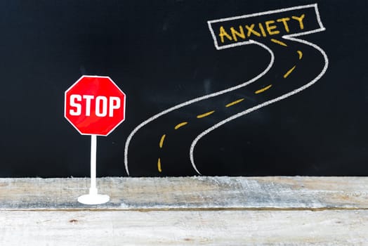 Mini STOP sign on the road to ANXIETY, hand drawing over chalkboard
