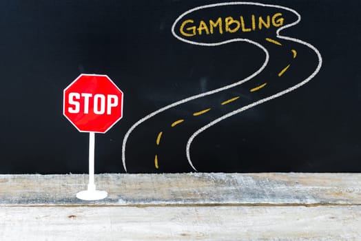 Mini STOP sign on the road to GAMBLING, hand drawing over chalkboard