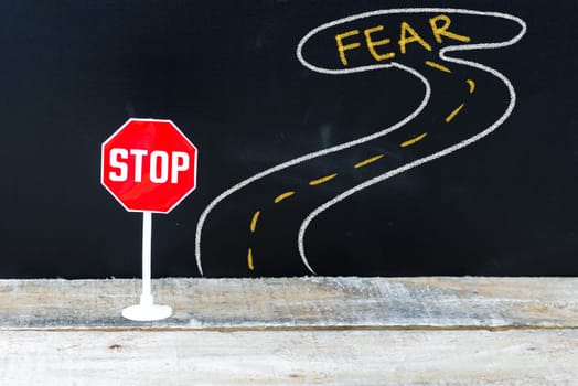Mini STOP sign on the road to FEAR, hand drawing over chalkboard