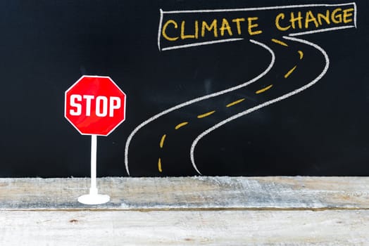 Mini STOP sign on the road to CLIMATE CHANGE, hand drawing over chalkboard