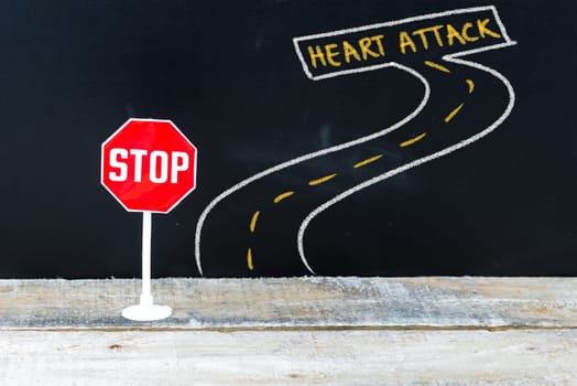 Mini STOP sign on the road to HEART ATTACK, hand drawing over chalkboard