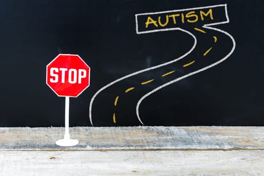 Mini STOP sign on the road to AUTISM, hand drawing over chalkboard