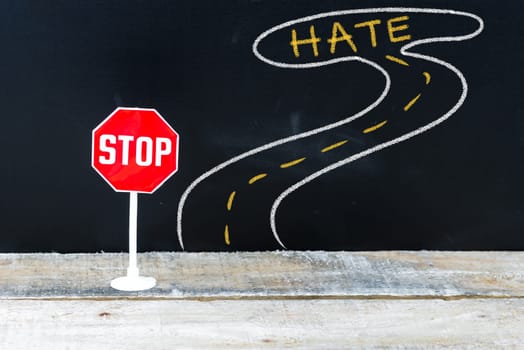 Mini STOP sign on the road to HATE, hand drawing over chalkboard