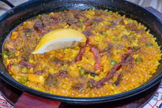 Gourmet Valencia paella with seafood and fresh cr lobes,squid and mussels with saffron rice and lemon slices,close-up..