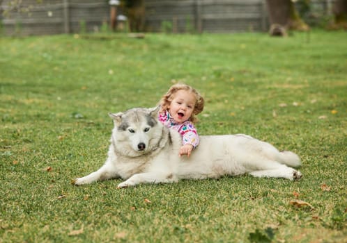 The little baby girl playing with dog against green grass in park