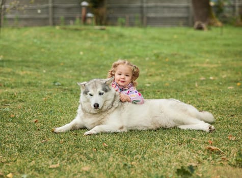 The little baby girl playing with dog against green grass in park