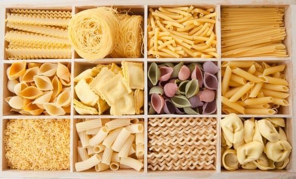 Different types of pasta sorted in boxes as a background