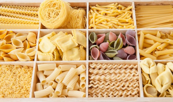 Different types of pasta sorted in boxes as a background
