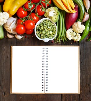 Green peas in a bowl with fresh vegetables on wood top view