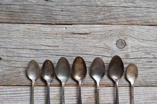 Vintage spoons with patina on old wooden table
