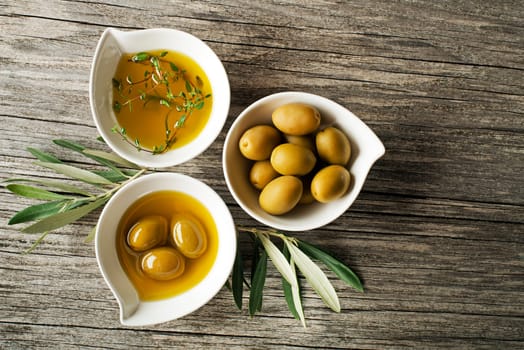 Olive oil with fresh herbs on wooden background