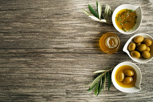 Olive oil with fresh herbs on wooden background