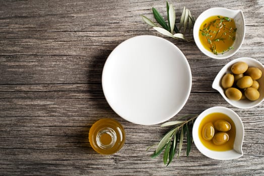 Olive oil with fresh herbs on wooden background