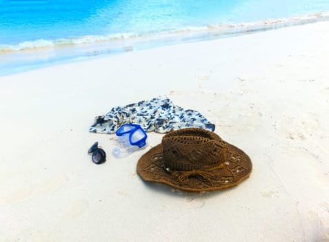 The straw hat, mask, sun glasses and dress on a tropical beach