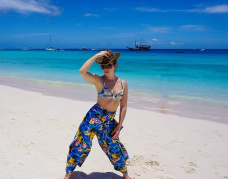Beautiful woman on the beach with hat against the sand. Beautiful pants in the style caribbean