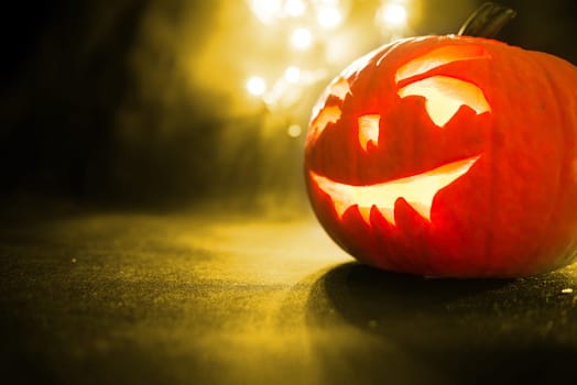 carved face of the pumpkin on yellow bokeh light background