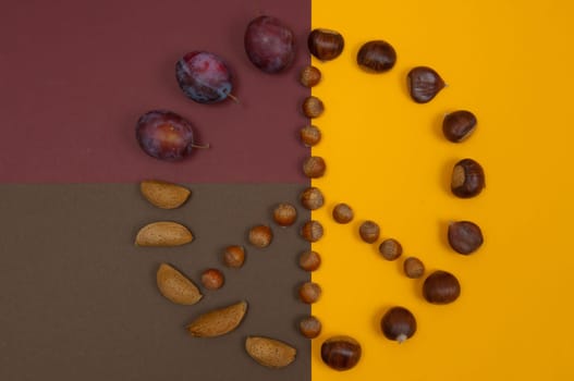 Peace symbol of in shell nuts and autumn fruits on split background