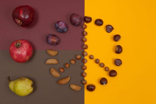 Peace symbol of in shell nuts and autumn fruits on split background